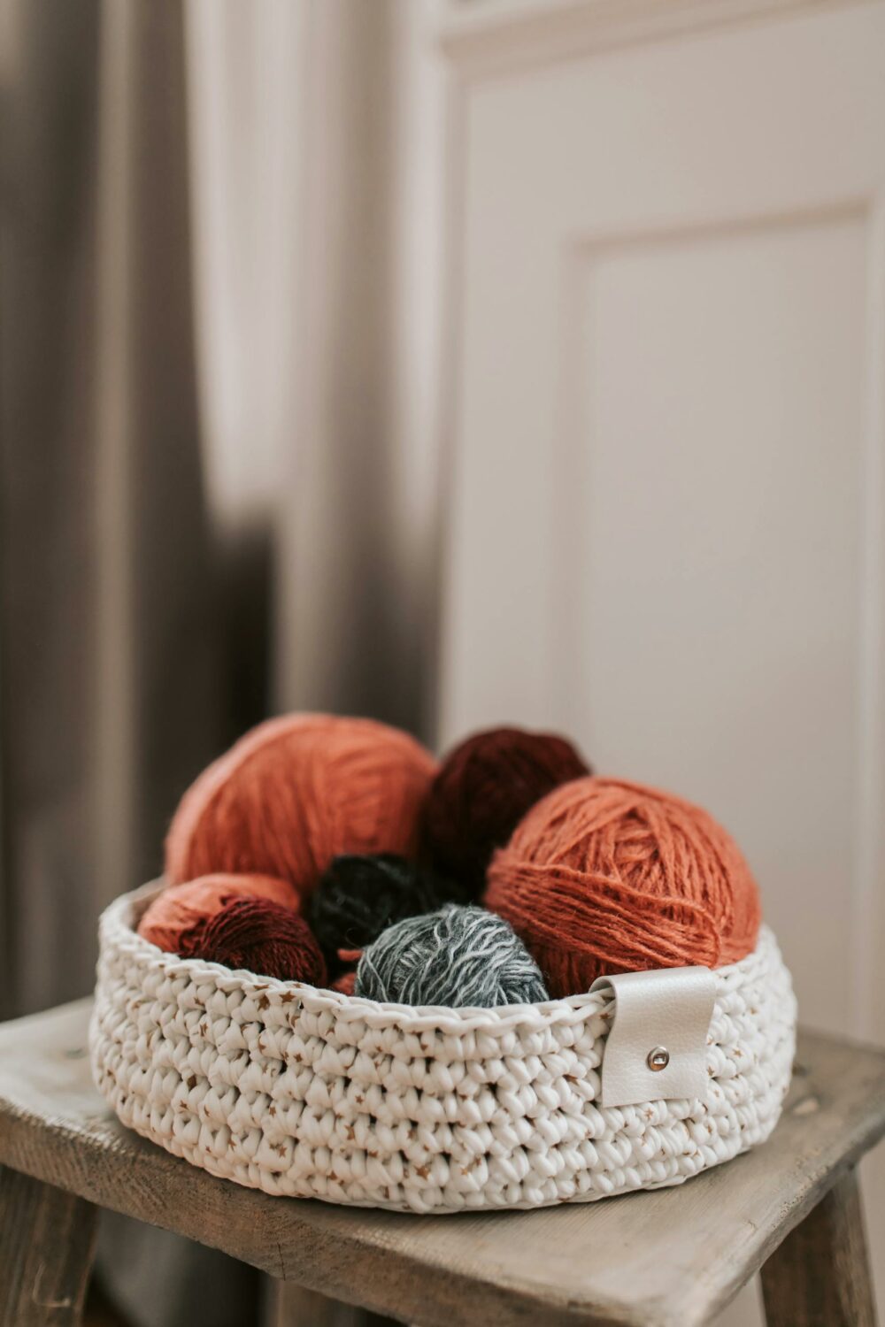 A woven basket filled with vibrant yarn balls, perfect for knitting and crafts.